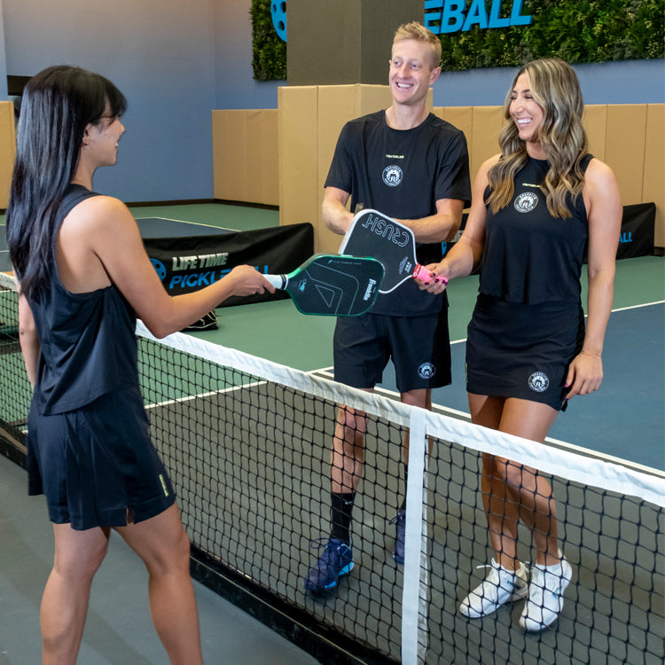 Three players meeting at the net during an indoor Brooklyn pickleball session