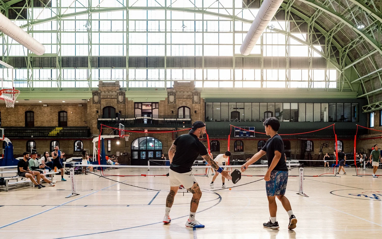 Players gathering around indoor courts during a New York pickleball event